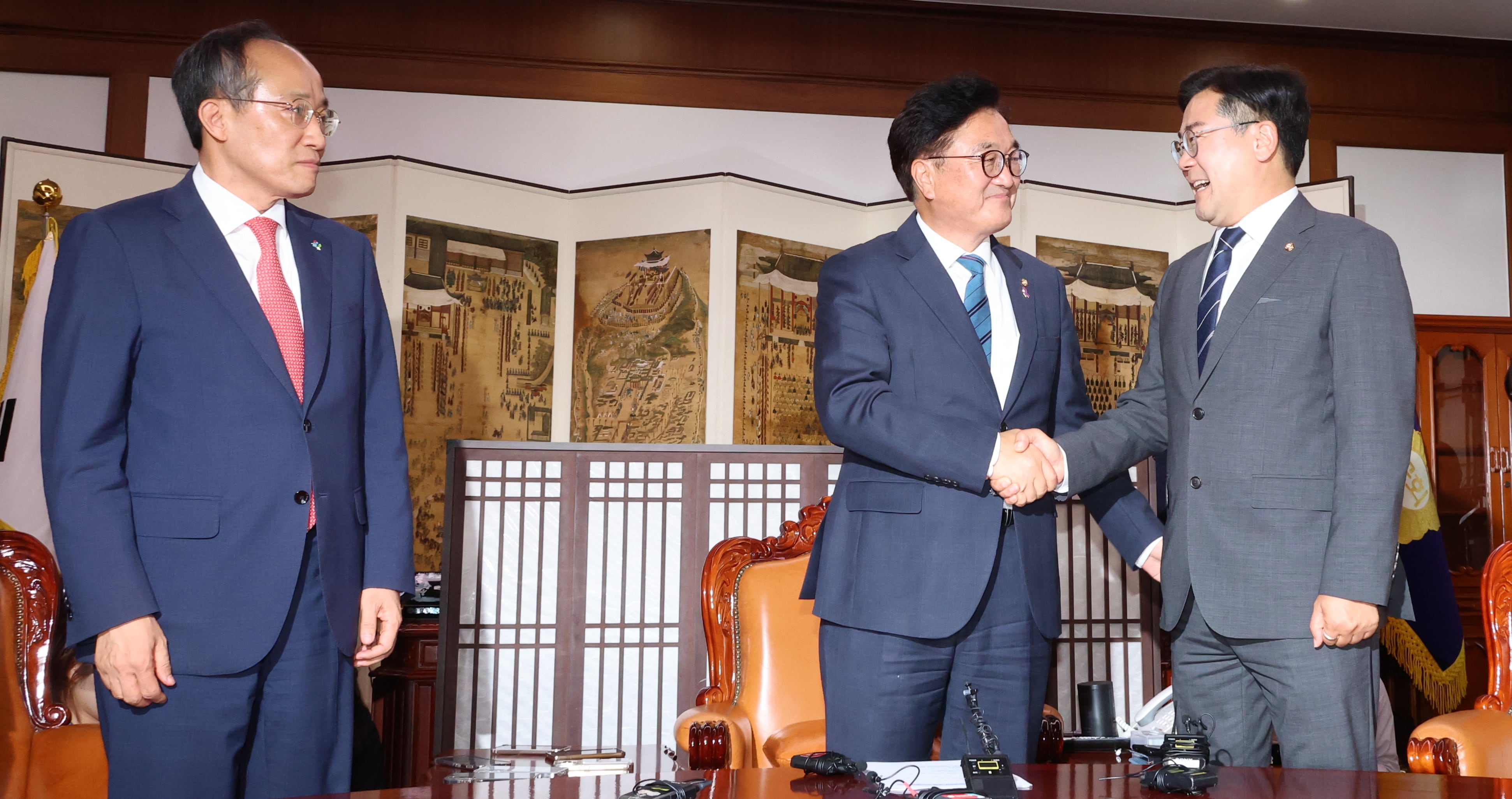 22대 국회 전반기 원 구성 협상을 위해 10일 국회의장실에 여야 원내대표가 모인 가운데, 더불어민주당 박찬대(오른쪽) 원내대표와 우원식(가운데) 국회의장이 웃으며 악수하는 모습을 국민의힘 추경호(왼쪽) 원내대표가 바라보고 있다. /연합뉴스