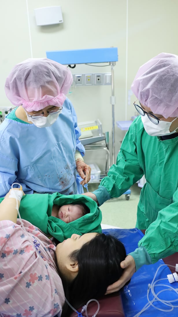 크리스마스 이브인 지난 24일 오후 창원한마음병원 분만실에서 산부인과 전문의 장석용 교수(왼쪽)가 둘째 딸 보늬씨, 사위와 함께 갓 태어난 손녀를 살펴 보고 있다. /창원한마음병원