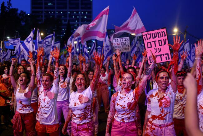 이스라엘 텔아비브 시위 현장. 2023년 5월 6일(현지시각) 베냐민 네타냐후 총리와 우파 연정의 ‘사법 장악’ 추진에 반대하는 시민들이 붉은 물감을 몸에 뿌린 채 시위를 벌이고 있다. 참가자들은 ‘손에 피를 묻힌 정부’ 등 반정부 구호가 적힌 팻말을 들고 항의의 뜻을 나타냈다. 사진=로이터·연합뉴스