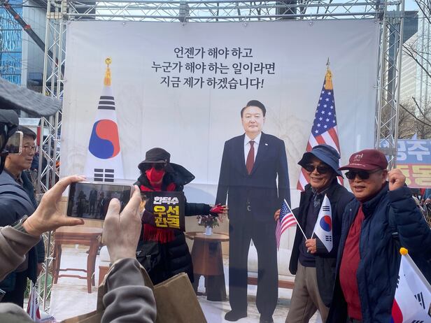 15일 광화문에서 열린 탄핵 반대 집회에 윤석열 대통령 포토존이 세워져 집회 참가자들이 사진을 찍고 있다./김혜민 기자